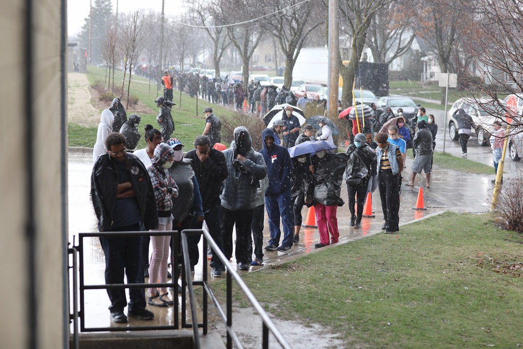 A long line of people in Wisconsin standing in the rain waiting to vote.